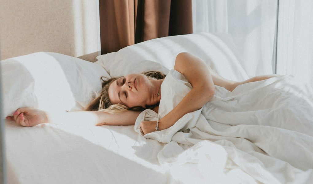 A woman asleep in a bed with white sheets
