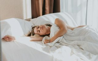 A woman asleep in a bed with white sheets
