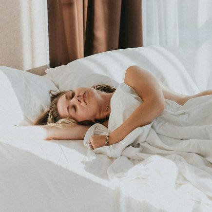 A woman asleep in a bed with white sheets