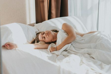 A woman asleep in a bed with white sheets