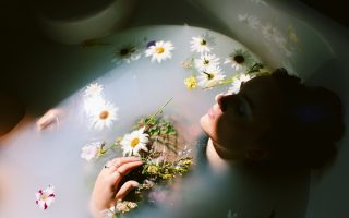 A woman relaxing in a bath with floating daisies
