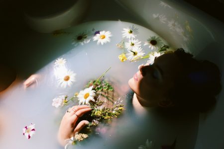 A woman relaxing in a bath with floating daisies