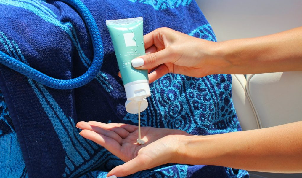 A person squeezing sunscreen from a tube into their hand
