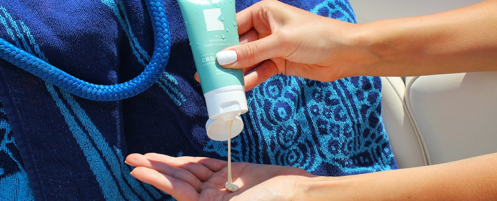 A person squeezing sunscreen from a tube into their hand