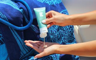 A person squeezing sunscreen from a tube into their hand